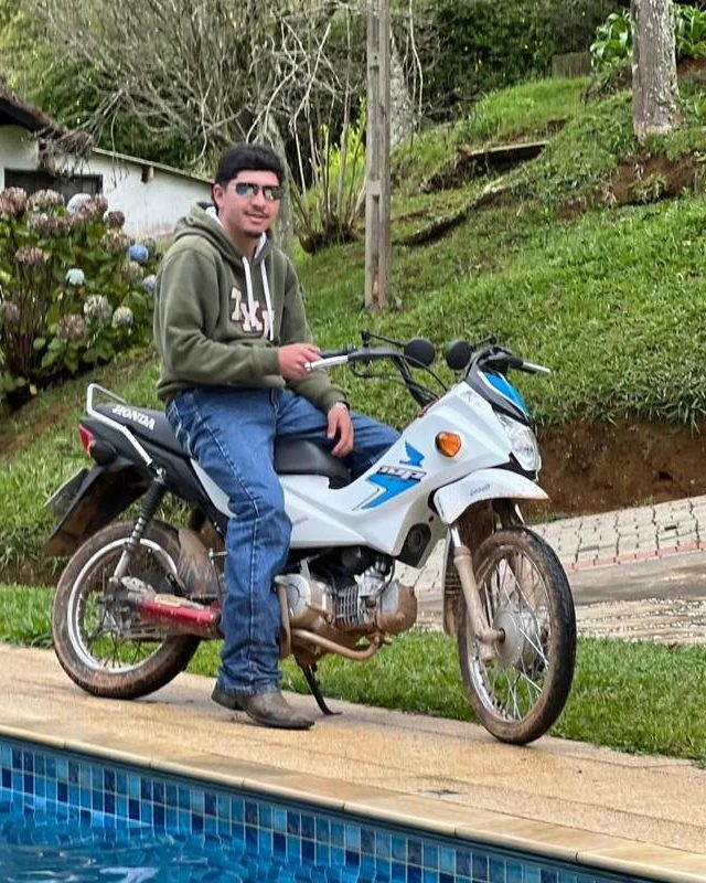 Kauê, guia da Trip Experience, sentado numa moto na base.