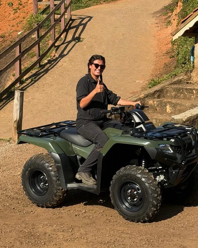 Yasmin, gerente da operação da Trip Experience, sentada num quadriciclo na base, fazendo sinal de positivo.